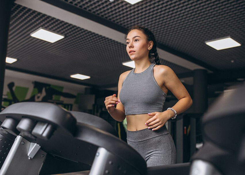 Девушка тренируется на беговой дорожке